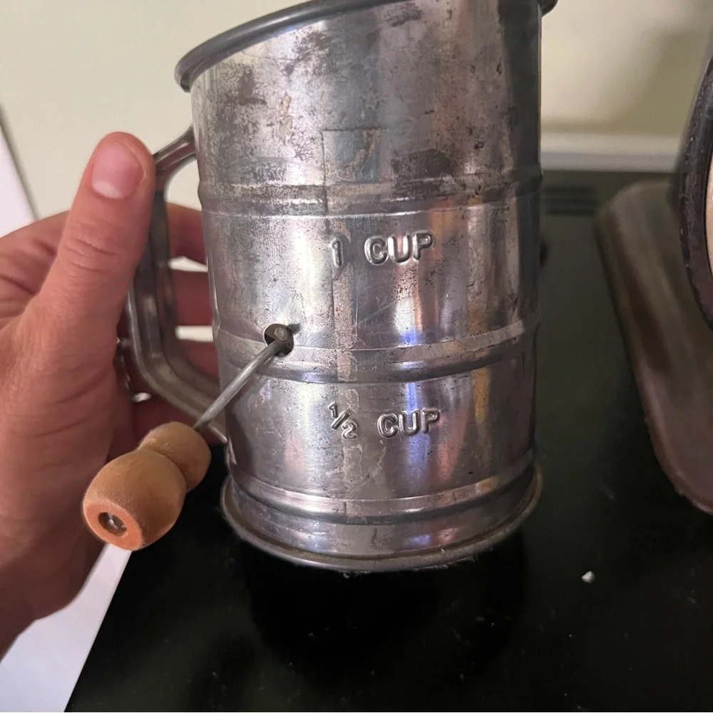 Antique, aluminum sifter with wooden handle.